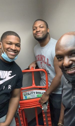 The Wright Move Team. They're With A Red Moving Cart. They're Smiling. Moving Services With Truck.